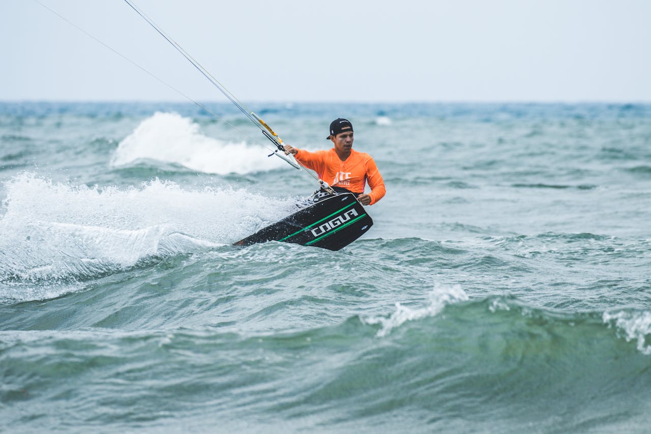 A man enjoys kite surfing on choppy sea waves with a clear sky.